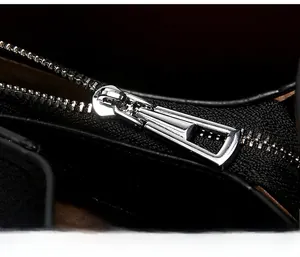 Macro shot of silver metal zipper detail on black soft leather tote bag for women