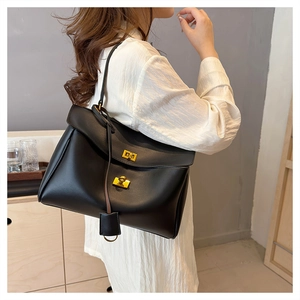 Close-up of black leather tote bag with dual gold twist locks and metal ring detail