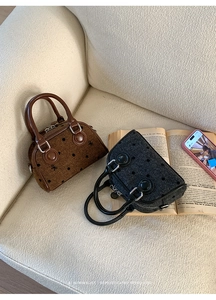 Detail of mini canvas boston bags with bow embroidery and polka dots on a sofa