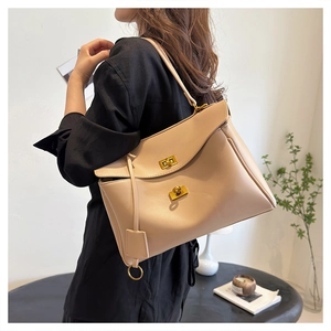 Close-up of minimalist beige tote bag with gold twist locks and soft leather texture