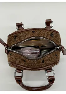 Internal capacity of brown woven cylinder bag showing space for phone and makeup