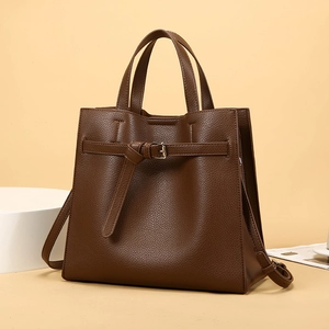 Close-up of brown litchi grain leather tote bag with retro buckle and dual handles