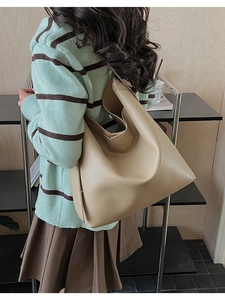 Dettaglio della borsa tote beige in pelle grana indossata da modella con forma morbida