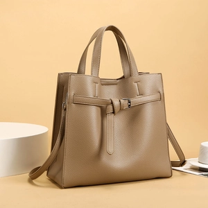 Detailed macro view of khaki pebbled leather texture on a stylish tote with knotted metal buckle
