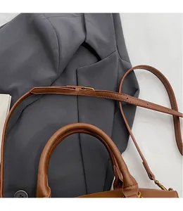 Détail de la bandoulière réglable en cuir et boucle métallique sur un sac fourre-tout marron