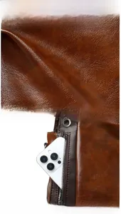 Macro shot of dark brown litchi grain leather texture and front zipper pocket detail