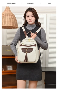 Detail of color-block backpack with beige textured leather and tassel charm on front pocket