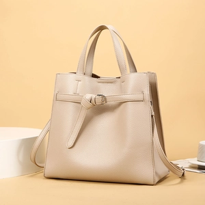 Detail of beige faux leather tote bag with lychee texture and metallic buckle strap