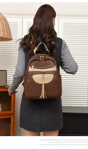 Detailed back view of a large two-tone brown and beige leather backpack on a model
