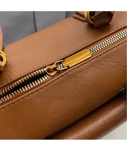 Détail d'une fermeture éclair en métal doré lisse sur un sac à main en cuir marron