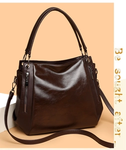 Detail of dark brown tote bag showing glossy leather texture and metal zipper accents