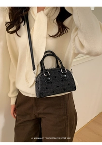 Close-up of a black retro textured baguette bag with leather strap on a model