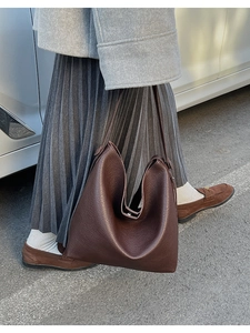 Texture dettagliata della pelle martellata marrone scuro su una borsa hobo minimalista