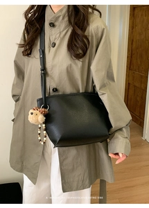 Détail du sac seau en cuir grainé noir avec un charmant pendentif chien en peluche