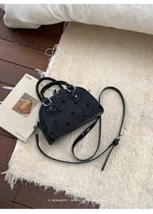 Detail of black woven leather Boston bag with polka dot pattern and adjustable strap