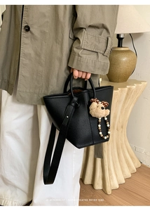 Détail du sac seau noir en cuir grainé avec pendentif ours et bandoulière amovible