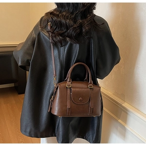 Vue détaillée du sac à main en cuir marron foncé avec bouton doré et bandoulière