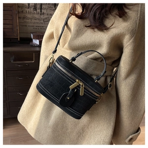 Detail of a vintage black crocodile embossed bucket bag with contrasting white stitching