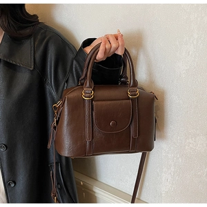 Sac à main Boston marron foncé avec texture vintage, détails dorés et poche frontale décorative