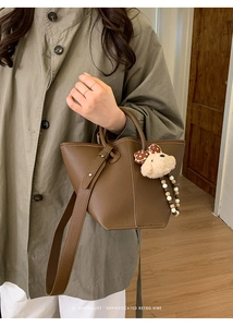 Détail du sac seau en cuir marron foncé avec un joli charm d'ours en peluche doux