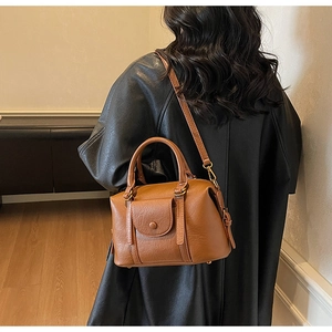 Sac docteur vintage marron porté sur un manteau noir pour l'effet de style