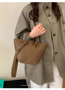 Détail du sac cabas en cuir grainé marron avec poignée tubulaire et sangle décorative