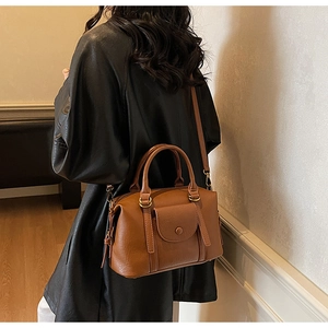 Gros plan sur le sac Boston vintage marron avec finitions dorées et poche à rabat