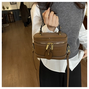 Detail of a brown crocodile embossed vanity bag with gold hardware and top handle