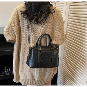 Détail d'un sac Boston noir vintage avec finition brillante et ferrures dorées rétro
