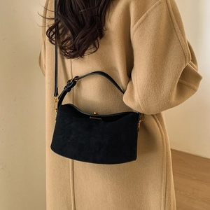 Detail of black suede hobo bag with smooth leather straps and vintage gold hardware