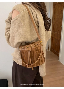 Macro detail of a vintage brown fringed bucket bag featuring long suede tassels and drawstring