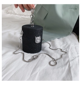 Detail of black glitter cylinder evening bag with silver chain and metal clasp closure