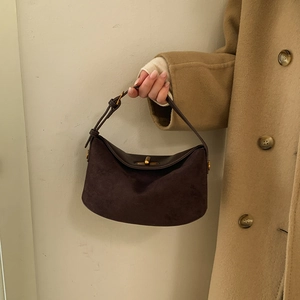 Detail of vintage chocolate suede handbag with gold twist lock on wool coat background
