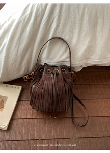 Detail of vintage dark brown fringe bucket bag with drawstring and gold metal eyelets