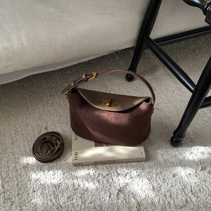 Detail of a dark brown retro crossbody bag featuring a golden twist lock and adjustable strap