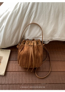Detail of a brown vintage bucket bag with layered tassels and drawstring closure