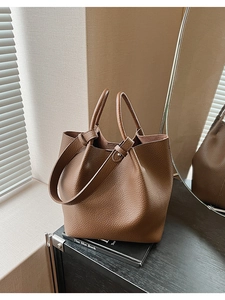 Detail of caramel lychee grain leather tote bag with cylindrical handle and strap