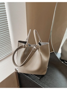 Detailed macro view of the taupe bucket bag with litchi texture and dual top handles