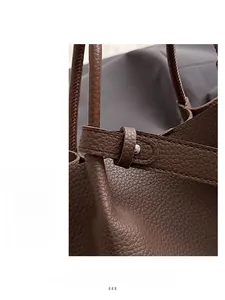 Close-up of litchi grain leather texture and silver hardware on dark brown bucket bag