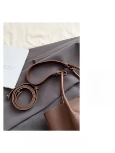 Detail of dark brown lychee leather bucket bag with adjustable strap and stitching