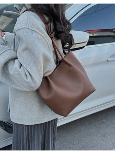Detailed macro view of the brown lychee grain texture on a soft leather tote bag