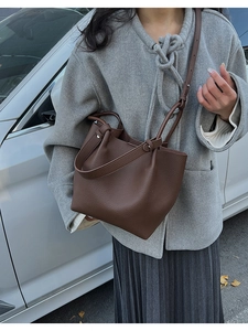 Detail of dark brown lychee textured leather bucket bag with wide handle and long strap