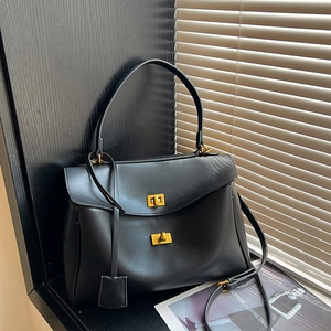 Minimalist black leather underarm tote bag with gold twist locks and adjustable strap