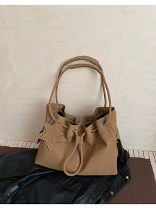 Detail view of khaki leather tote bag featuring drawstring closure and star charm
