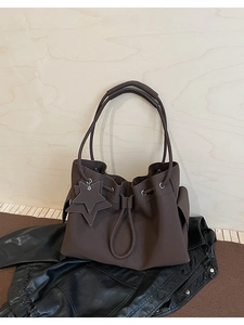 Detail view of brown faux leather bucket bag with star pendant and drawstring closure
