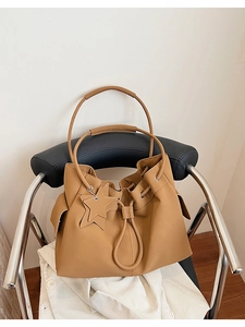 Close-up of brown litchi pattern tote bag with drawstring detail and star pendant