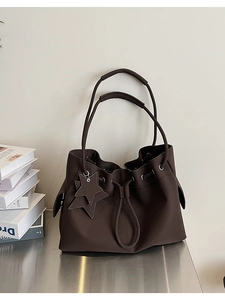 Detail view of dark brown pebbled leather tote with drawstring closure and star charm