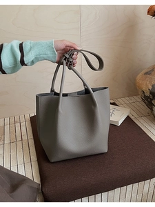 Detailed shot of grey bucket bag with lychee texture and slim leather handles
