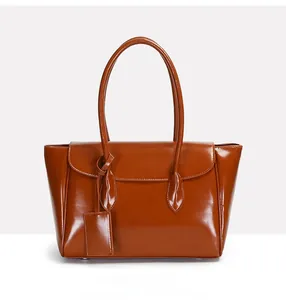 Detail of vintage brown tote bag with glossy oil leather texture and square leather tag