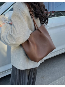 Close-up of a large brown pebble leather tote bag shown on a model for daily commute